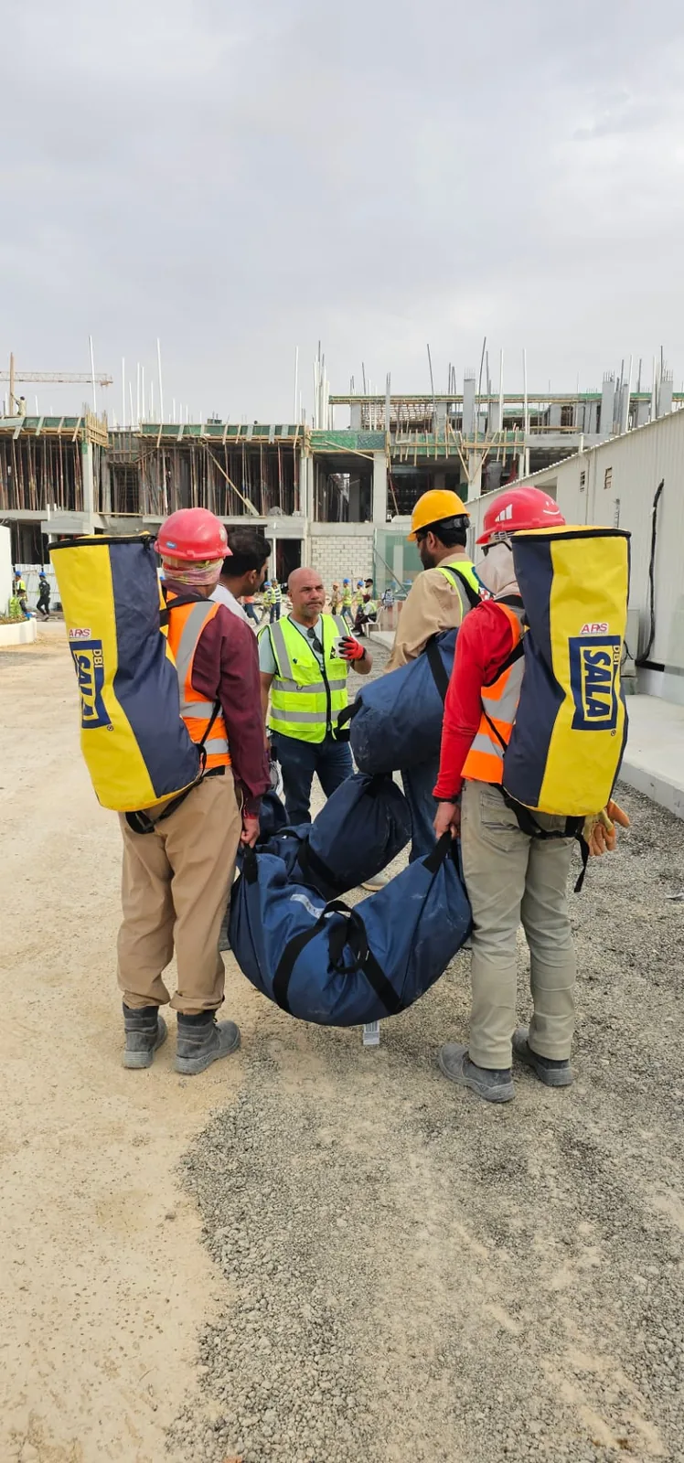 ARS rescue team carrying a rescue litter and rescue kit bags across an active construction site