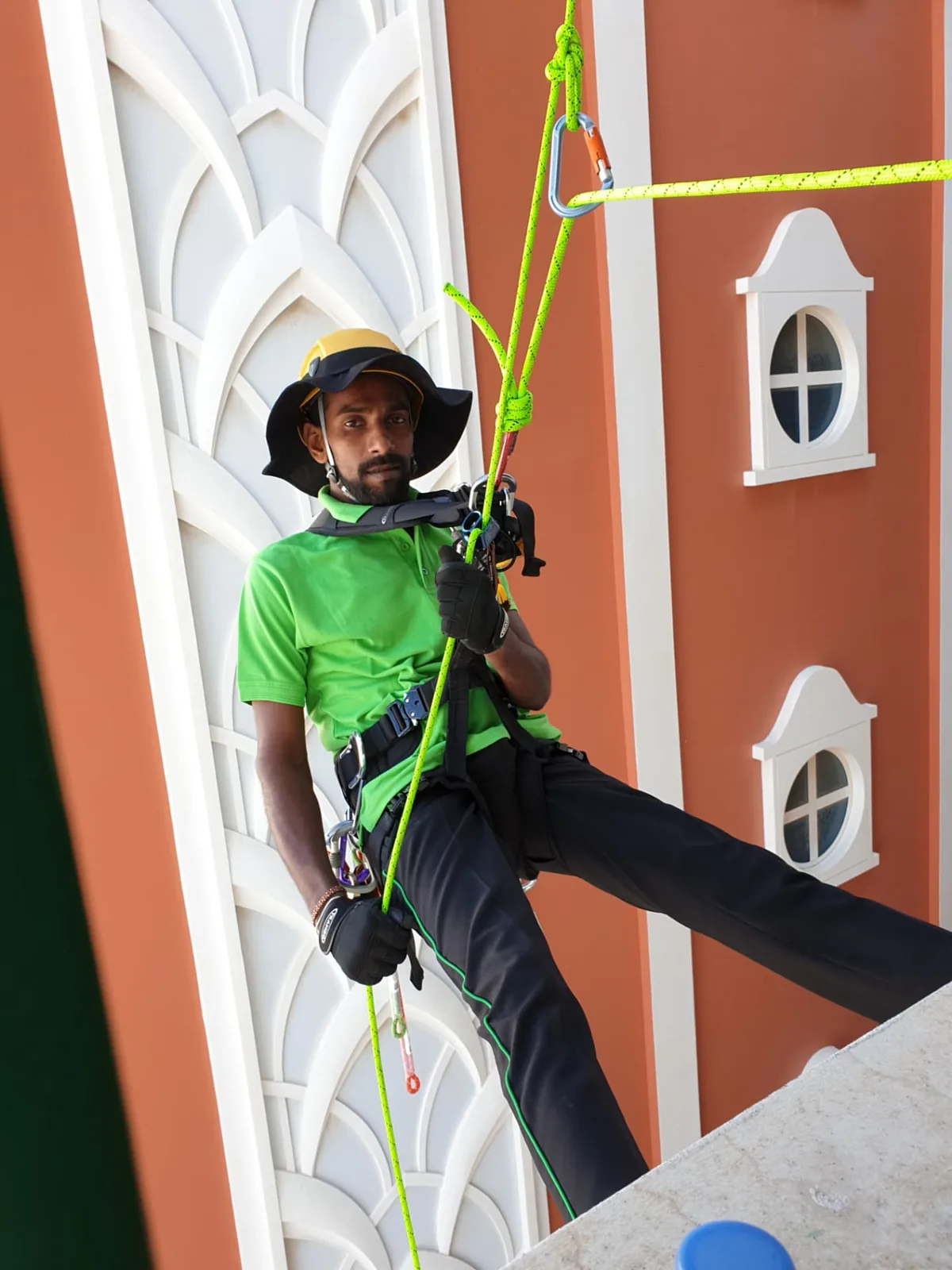 ARS rope access technician in harness rappelling a building facade on twin ropes